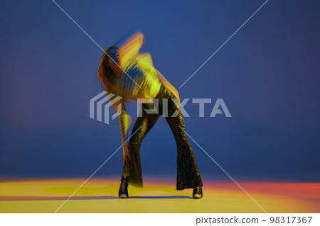 Portrait of young girl dancing heels dance in stylish clothes over blue background in neon light with mixed lights. Concept of modern dance style 98317367