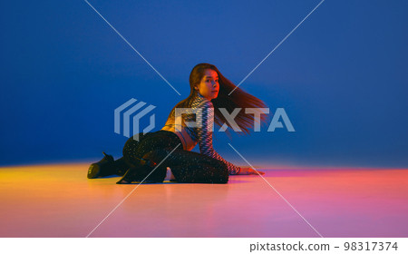 Warming up. Portrait of young girl dancing heels dance in stylish clothes over blue background in neon light. Concept of modern dance style 98317374