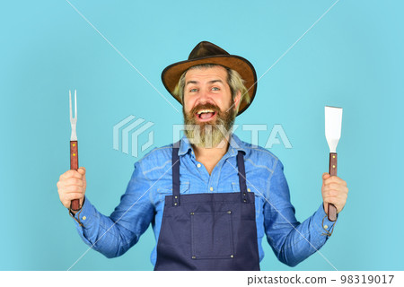 Farmer promoting bbq equipment. Cooking steak. Cooking utensils. Summer picnic. Bbq american tradition. Culinary concept. Medium rare. Bbq food. Tools roasting meat. Man in apron hold barbecue grill Farmer promoting bbq equipment. Cooking steak. Cooking utensils. Summer picnic. Bbq american tradition. Culinary concept. Medium rare. Bbq food. Tools roasting meat. Man in apron hold barbecue grill 98319017
