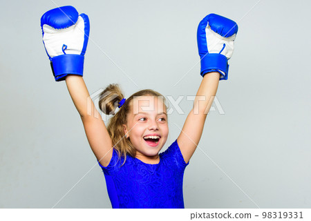 Girl child happy winner with boxing gloves posing on grey background. Feminist movement. She feels as winner. Upbringing for leadership and winner. Strong child proud winner boxing competition Girl child happy winner with boxing gloves posing on grey background. Feminist movement. She feels as winner. Upbringing for leadership and winner. Strong child proud winner boxing competition 98319331