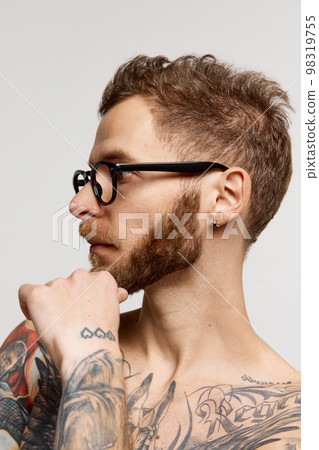 Close up portrait of charming bearded man in eyewear looking at camera confidently over grey background. Concept of emotions, mental health, fashion 98319755