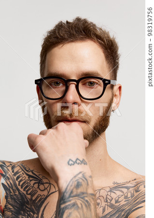 Close up portrait of charming bearded man in eyewear looking at camera confidently over grey background. Concept of emotions, mental health, fashion 98319756