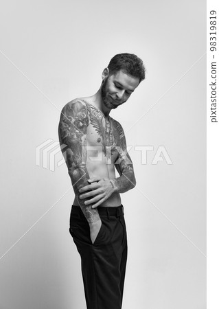 Portrait of muscular male fashion model posing isolated over grey studio background. Masculinity. Concept of men's health, beauty, body and skin care, fitness. Body art 98319819