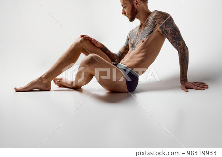 Portrait of muscular male fashion model posing isolated over grey studio background. Masculinity. Concept of men's health, beauty, body and skin care, fitness. Body art 98319933