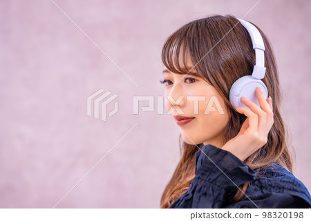 A woman listening to music with headphones A woman listening to music with headphones 98320198