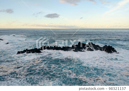 View of the waves crashing against the cliffs of the island. Beautiful sea surface. Ocean landscape. 98321137