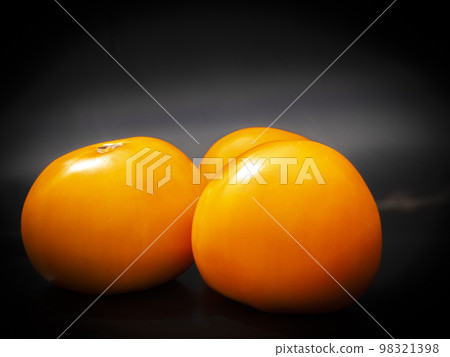 Yellow tomatoes vegetables on a black background. Yellow tomatoes vegetables on a black background. 98321398