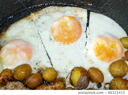 Scrambled eggs and fried potatoes in a pan. 98321415