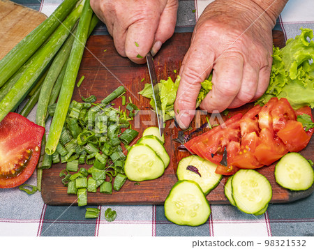 Slicing green lettuce with a knife on a cutting board. Slicing green lettuce with a knife on a cutting board. 98321532