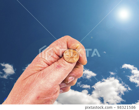 Hand with money coins on a background of blue sky. 98321586