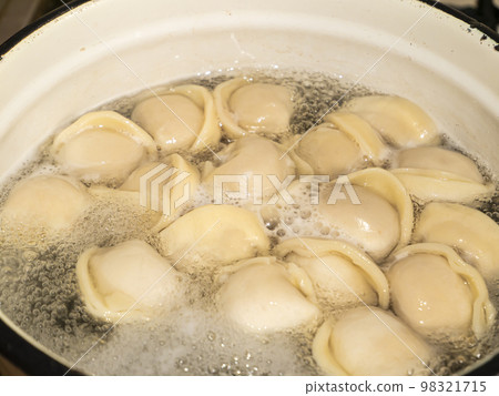 Dumplings from the dough with meat are boiled in boiling water. 98321715