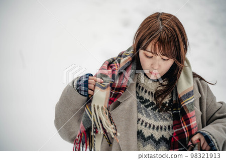 A woman enjoying wearing a checked scarf in the snow A woman enjoying wearing a checked scarf in the snow 98321913