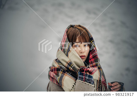 A woman enjoying wearing a checked scarf in the snow 98321917