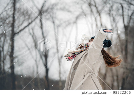 A woman playing by throwing snow in the snowy mountains A woman playing by throwing snow in the snowy mountains 98322266