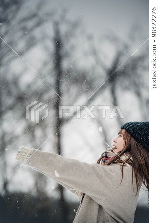 A woman playing by throwing snow in the snowy mountains 98322276
