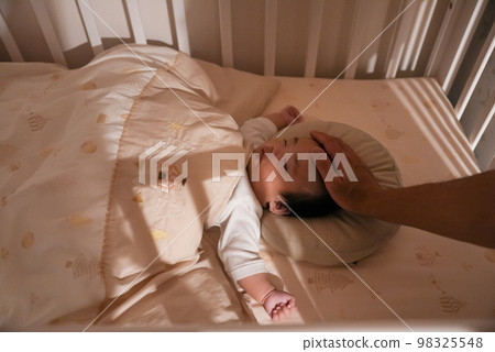 The figure of a baby being put to sleep at night by being stroked by his father 98325548