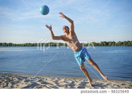 A beach volleyball player in action on a sunny day by the river A beach volleyball player in action on a sunny day by the river 98325649