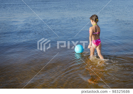 A little girl with blue ball playing in the water. A healthy way of life 98325686