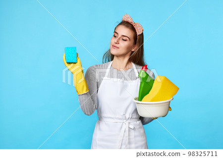 woman in rubber gloves cleaning with blue sponge and bottle of detergent 98325711