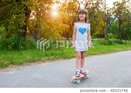 Cute girl riding a skateboard in the park at sunset. Healthy lifestyle 98325740