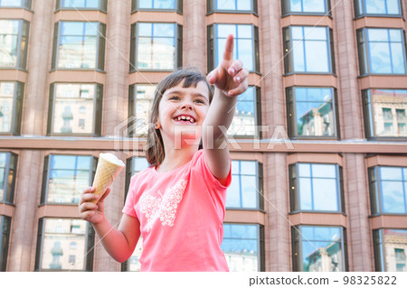 Smiling girl with ice cream in hands on the street in the city Smiling girl with ice cream in hands on the street in the city 98325822