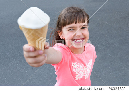 Adorable little girl eating ice-cream outdoors at summer in the city Adorable little girl eating ice-cream outdoors at summer in the city 98325831