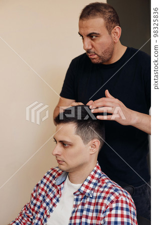 Barber and satisfied bearded man in front of the mirror Barber and satisfied bearded man in front of the mirror 98325836