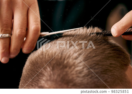 hairdresser does hairstyle with scissors in barber shop 98325851