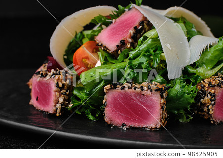 Tuna salad with parmesan on black plate on black concrete background Tuna salad with parmesan on black plate on black concrete background 98325905
