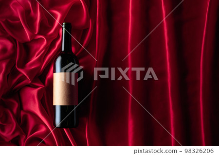 Bottle of red wine with an empty label on a satin background. 98326206