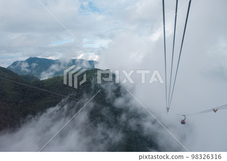 Cable car carries passenger moving on the mountain among the foggy in cloudy day at Sapa 98326316