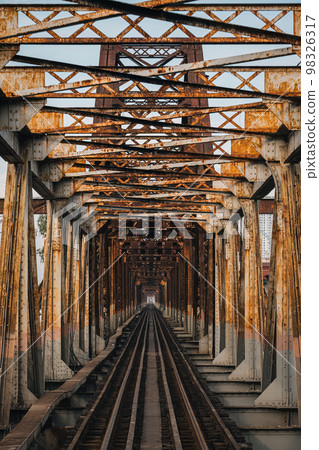 Old rusty iron traditional railway Long Bien bridge structure over the road in Hanoi city 98326317