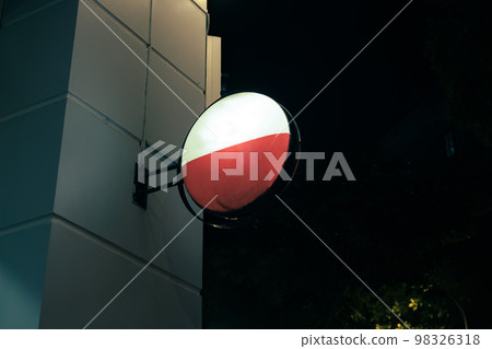 Illuminated empty signboard hanging on edge of store building in the night 98326318