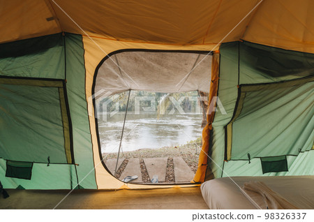 Inside of large comfortable camping tent on campground in the tropical forest by riverside on vacation 98326337