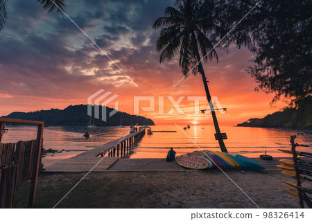 Beautiful sunset over tropical sea and wooden bridge, sightseeing boat and tourist enjoying in Koh Kood beach 98326414