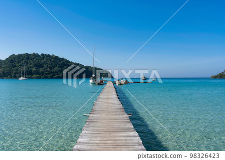 Scenery of wooden pier in the tropical sea and sightseeing boat anchored in sunny day on summer at Koh Kood 98326423