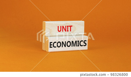 Unit economics symbol. Concept words Unit economics on wooden blocks. Beautiful orange table orange background. Business and unit economics concept. Copy space. 98326800