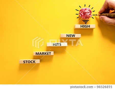 Stock market hits new high symbol. Concept words Stock market hits new high on wooden blocks on a beautiful yellow background. Businessman hand. Business stock market hits new high concept. Copy space 98326855