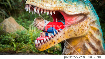 Educational toy park for kids. Boy is playing in the dinosaurs mouth. School boy learning fossils and reptiles. Children play with dinosaur toys. Evolution and paleontology game for young kid. Educational toy park for kids. Boy is playing in the dinosaurs mouth. School boy learning fossils and reptiles. Children play with dinosaur toys. Evolution and paleontology game for young kid. 98326903
