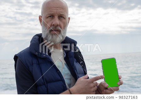 Mockup image of a grey-haired bearded man pointing his finger at a phone Mockup image of a grey-haired bearded man pointing his finger at a phone 98327163