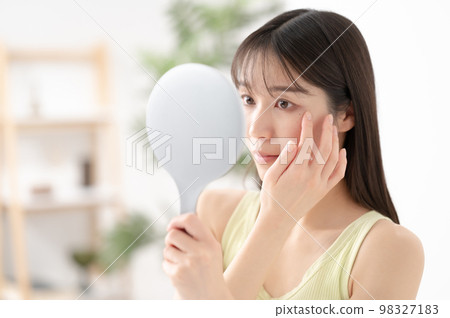 A woman who worries about her mole while looking in the mirror 98327183