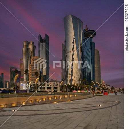 Doha corniche  sunset shot showing west bay skyscrapers and the promenade  with locals and visitors walking 98327408