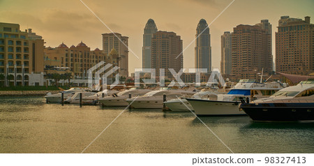 Porto Arabia Marina in The pearl , Doha, Qatar  sunset  shot showing luxurious yachts and boats docked at the marina with  residential buildings in background.  98327413
