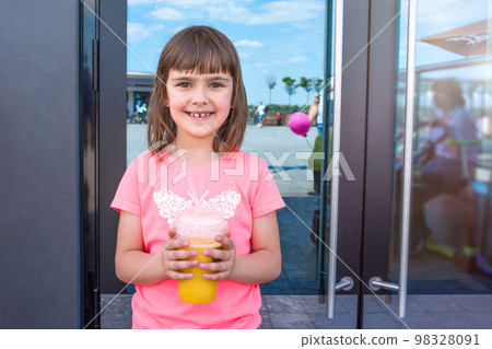 The happy lovely girl with orange juice at an entrance to cafe 98328091