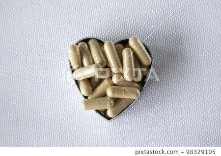 Transparent drug capsule pills with beige medication in pile heart shape Transparent drug capsule pills with beige medication in pile heart shape 98329105