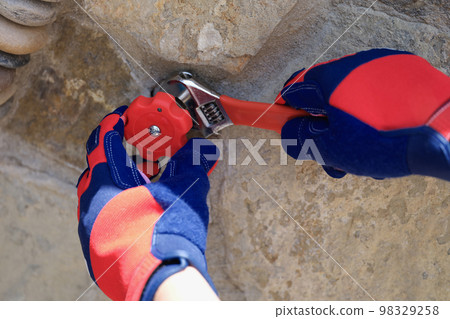 Handyman in gloves with wrench fixing water pipes oudoor. Handyman in gloves with wrench fixing water pipes oudoor. 98329258