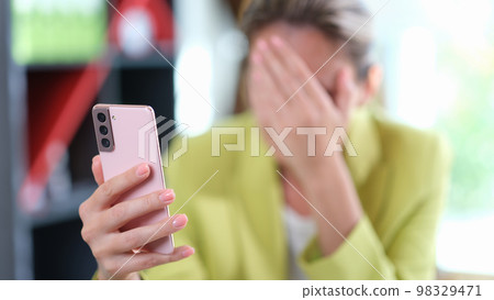 Sad woman covered her face with her hand while reading messages on her mobile phone. Sad woman covered her face with her hand while reading messages on her mobile phone. 98329471