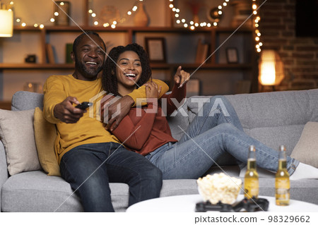 Joyful african american couple watching TV together at home 98329662