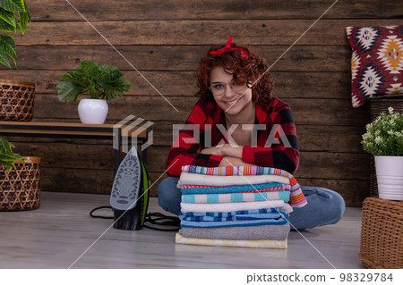 The girl sits on the floor and leans on freshly washed and ironed towels. 98329784