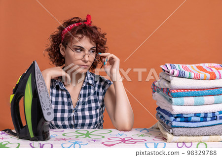 A girl with glasses glances at some ironed towels. Curly hair. A girl with glasses glances at some ironed towels. Curly hair. 98329788